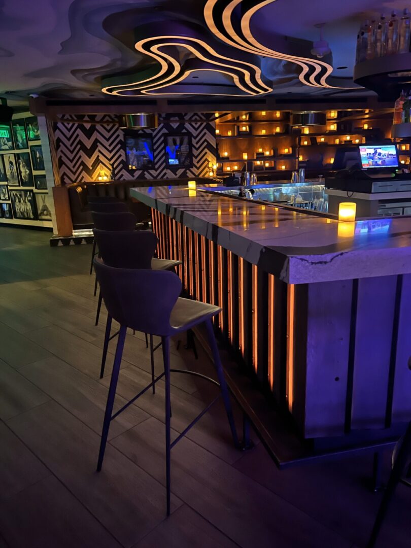 A bar with chairs and lights in the background