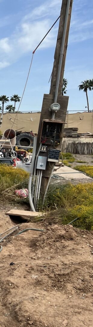 A rusted meter sitting in the grass near some trash.